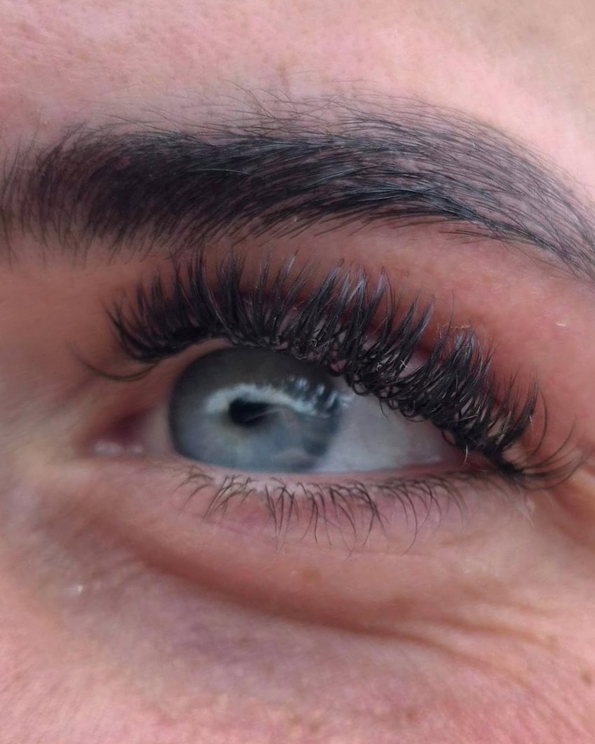 Gevormde wenkbrauw en volle wimpers bij een blauw oog
