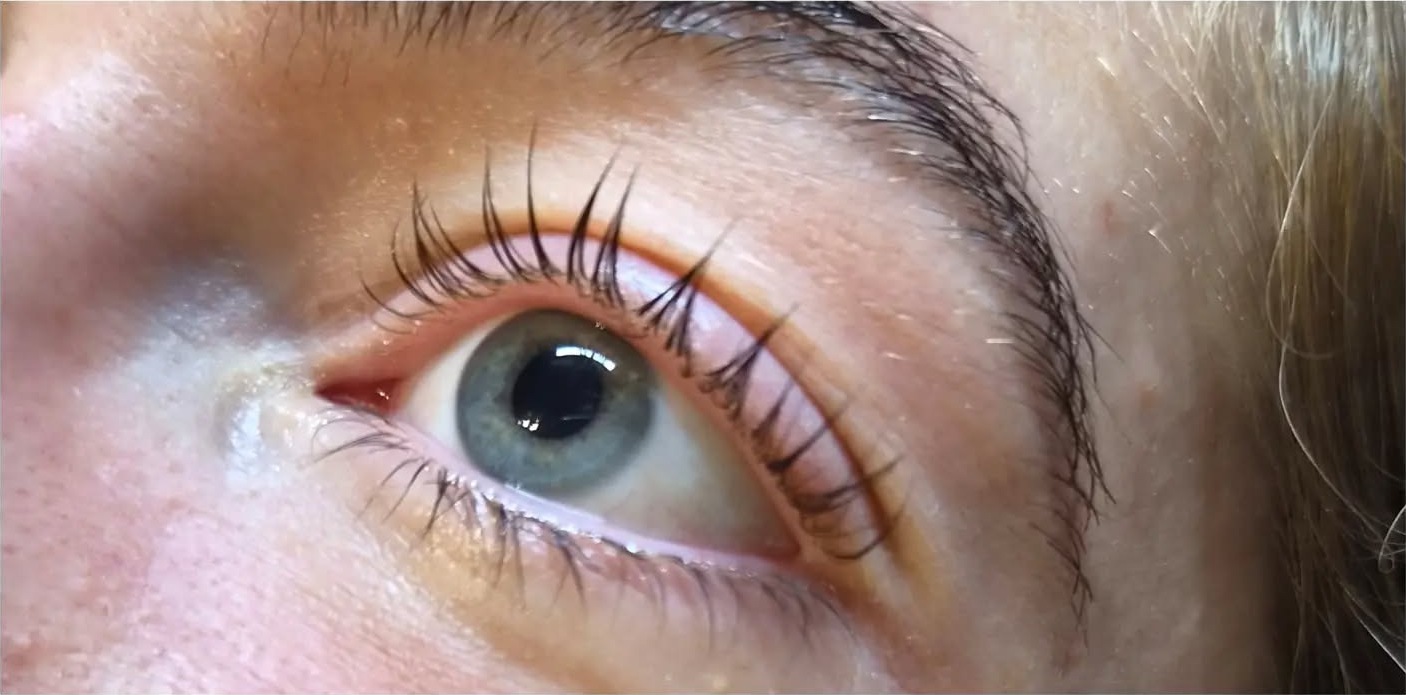 Een wimperlifting: gekrulde, geverfde wimpers bij een grijsblauw oog